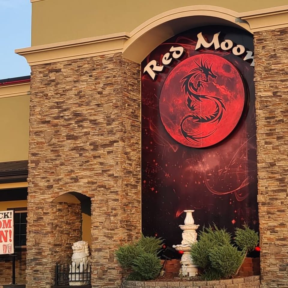 The exterior of Red Moon restaurant, featuring a large red dragon logo and stone facade.